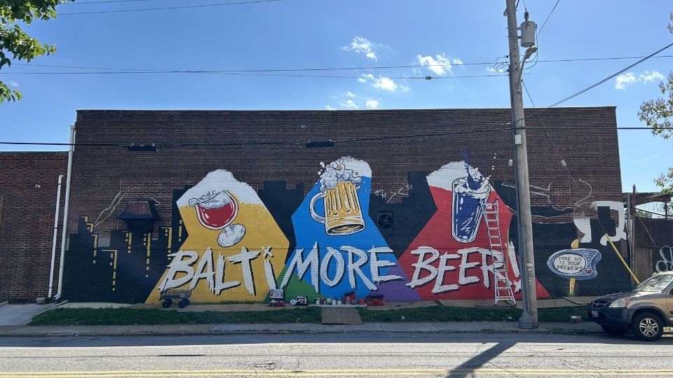 A wide, colorful 'Baltimore Beer' mural painted across a brick warehouse wall in the district.